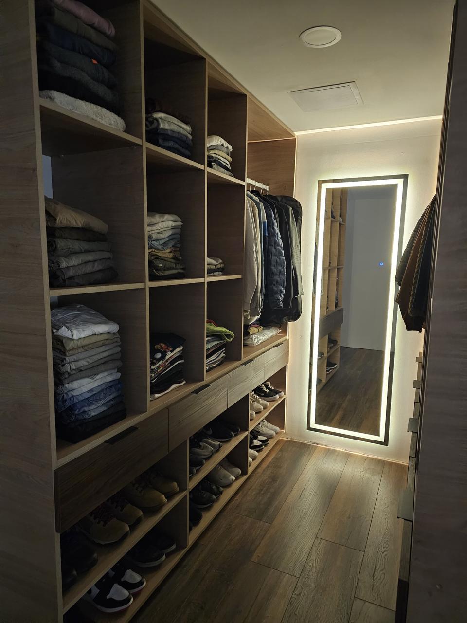 Vestidor a medida con módulos abiertos, cajones y espejo iluminado